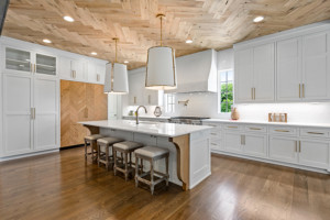 Beautiful luxury kitchen with wood floors and marble countertops - island seating and barnwood doors